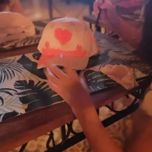 Crianças pintando bonés em oficina infantil criativa em Americana