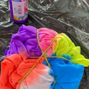 Oficina Infantil Tie Dye Camisetas Tecidos amarrados com elásticos recebendo pigmentos têxteis